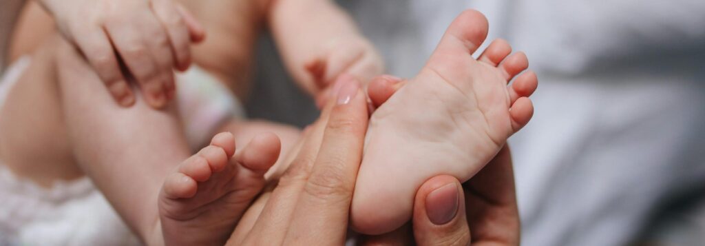 A close-up of a parent's hands gently massaging a baby's feet, showcasing tenderness and care.
